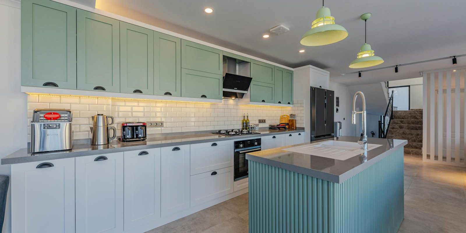 A kitchen with green cabinets and white counter tops