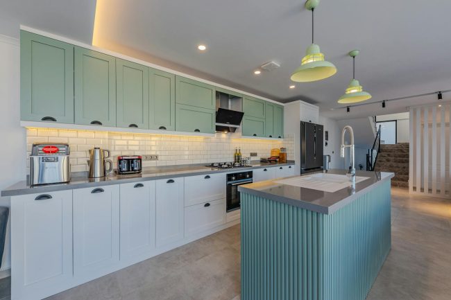 Photo by Ahmet ÇÖTÜR A kitchen with green cabinets and white counter tops