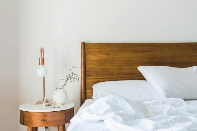 Photo by Burst White Bedspread Beside Nightstand With White and Copper Table Lamp