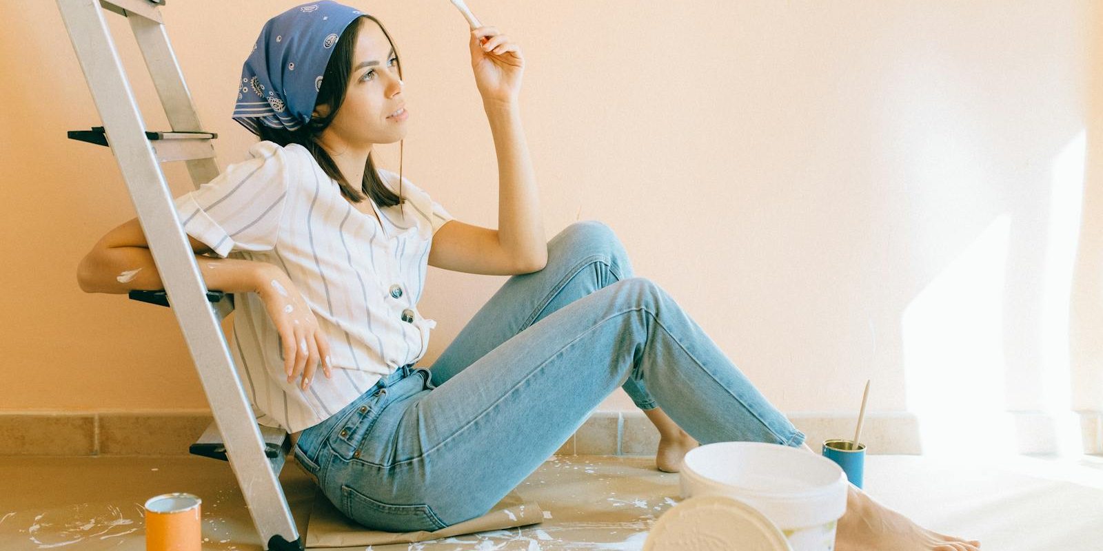 Photo by Nataliya Vaitkevich Woman Sitting on the Floor Holding a White Paintbrush
