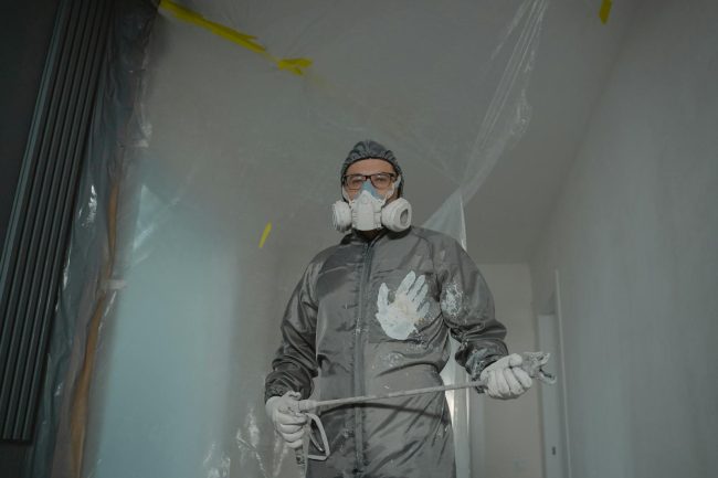 Photo by Tima Miroshnichenko A Person in Gray Suit Painting a House