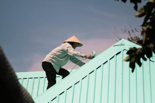 Photo by Nguyen Huy Man in Conical Hat Working on Roof
