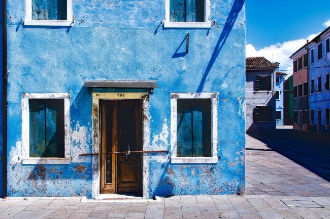 Photo by Pixabay An old, rustic blue building with wooden windows captured in bright daylight on an empty street.