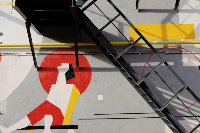 Photo by ready made Black metal staircase installed near gray wall with colorful graffiti on facade of modern building on street in city